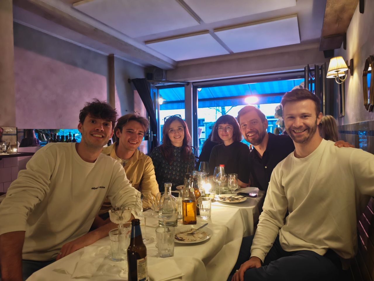 Six people smiling around a restaurant table at the cohort 1 wrap-up dinner